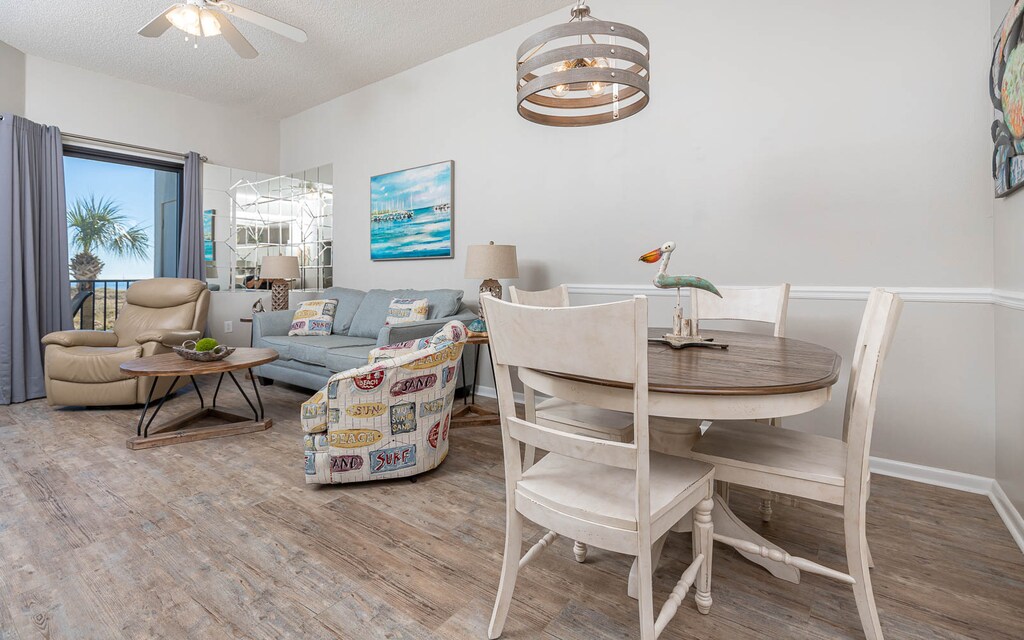 Living area features a cozy sofa with queen sleeper, dining table, and inviting decor, with a view of the beach