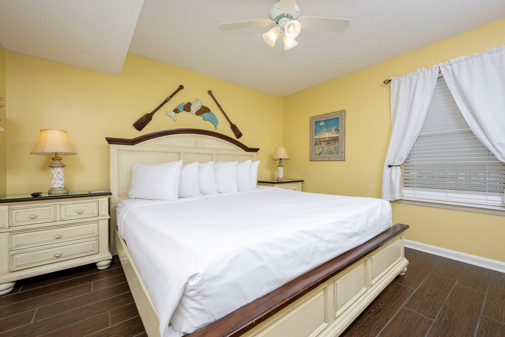 Bright yellow walls complement the coastal decor in this inviting bedroom featuring a king bed and nightstand
