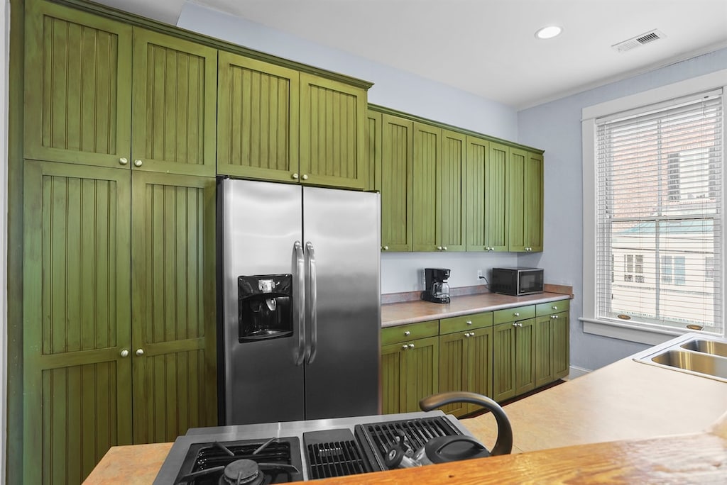 Sage green cabinetry and modern touches—this kitchen is a true centerpiece.