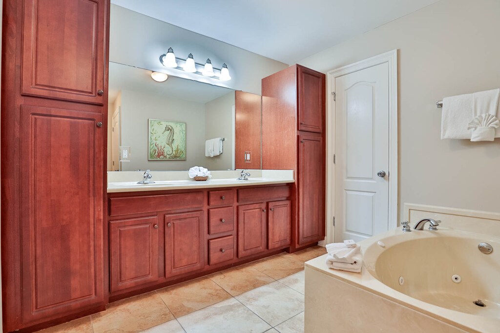 The master bath features rich wooden cabinetry, dual sinks, and a relaxing jetted tub for a soothing retreat