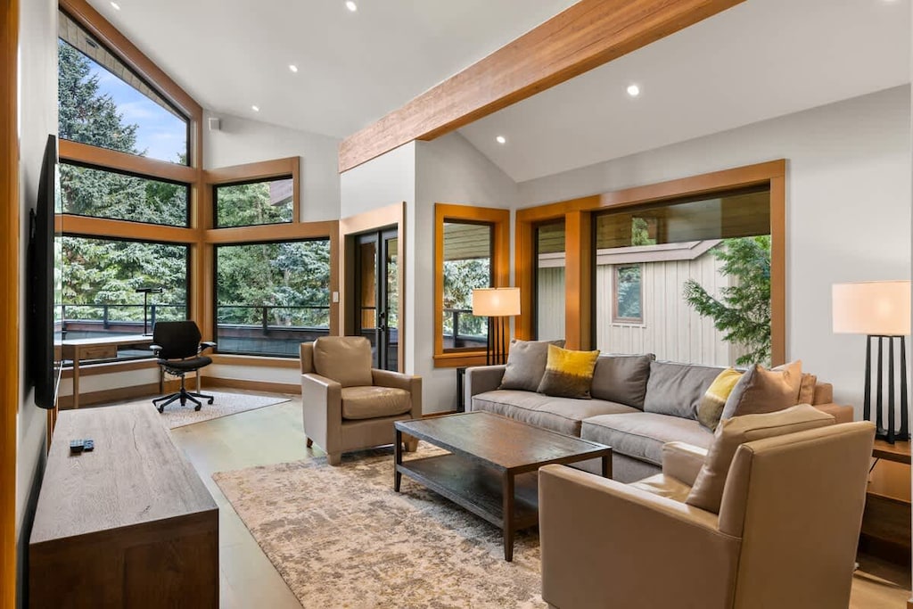 - Bright open living area with vaulted ceilings and forest-view windows  
- Cozy seating and modern decor create a warm mountain atmosphere  
- Perfect for relaxing after hiking or skiing in nearby trails  