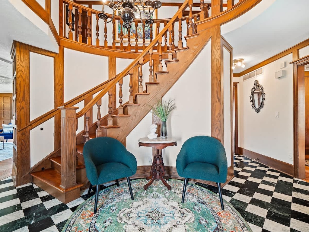 Grand entry w/ sweeping staircase, chandelier & patterned floors creating a striking first impression.