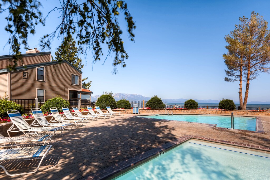 Lakefront pool deck with loungers overlooking scenic mountain and water views, perfect for relaxing sunny afternoons.