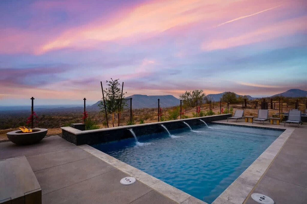 Estate 2: Stunning private oasis featuring a sparkling blue pool with sun loungers, a patio with a BBQ grill, outdoor furnishings for lounging and dining, and a fire pit surrounded by unparalleled desert views.