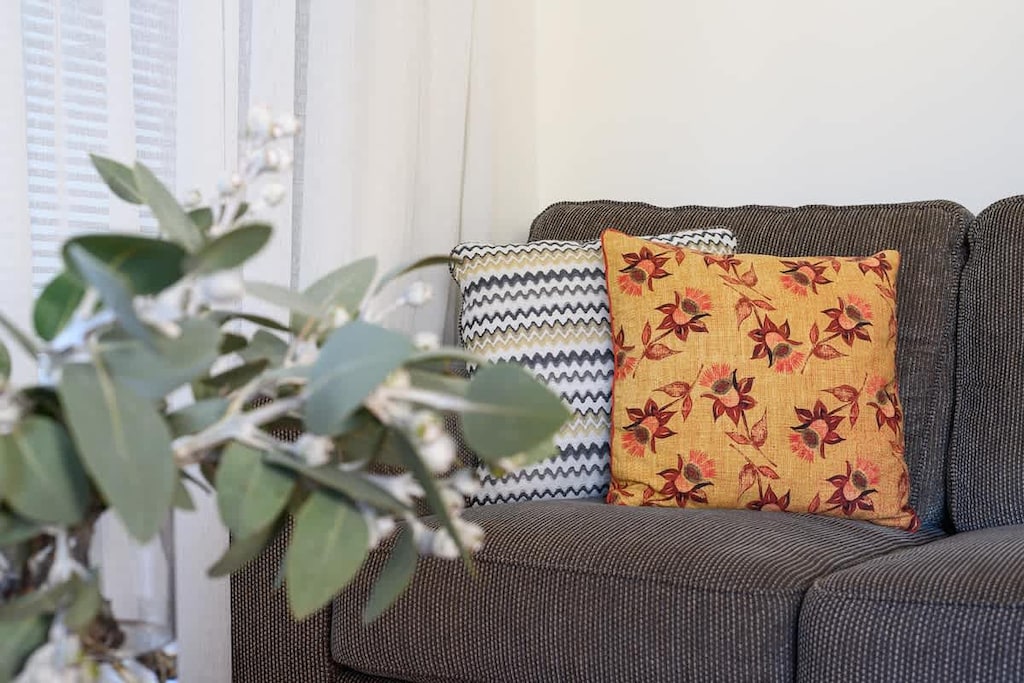 Discover a cozy corner designed for relaxation, featuring a comfortable sofa, inviting cushions, and fresh greenery to brighten your day.