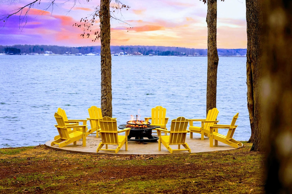 This inviting fire pit area offers a perfect gathering spot surrounded by nature, with Adirondack chairs arranged for enjoying the lake view and cozy fireside evenings.
