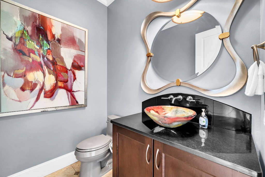 Your stylish powder room features an artistic vessel sink and statement mirror just off the kitchen.