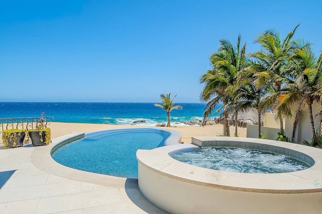 Soak in your private hot tub steps from the pool, with swaying palms, golden sand, and endless turquoise ocean stretching before you—pure beachfront bliss.