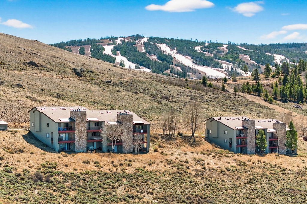 Modern mountain condominiums nestled in pristine high desert landscape with ski slopes visible on forested mountainsides.