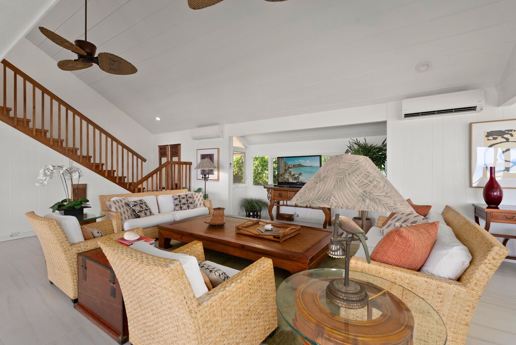 Unwind in your elegant living room where wicker chairs and soft cushions invite relaxation beneath tropical ceiling fans.