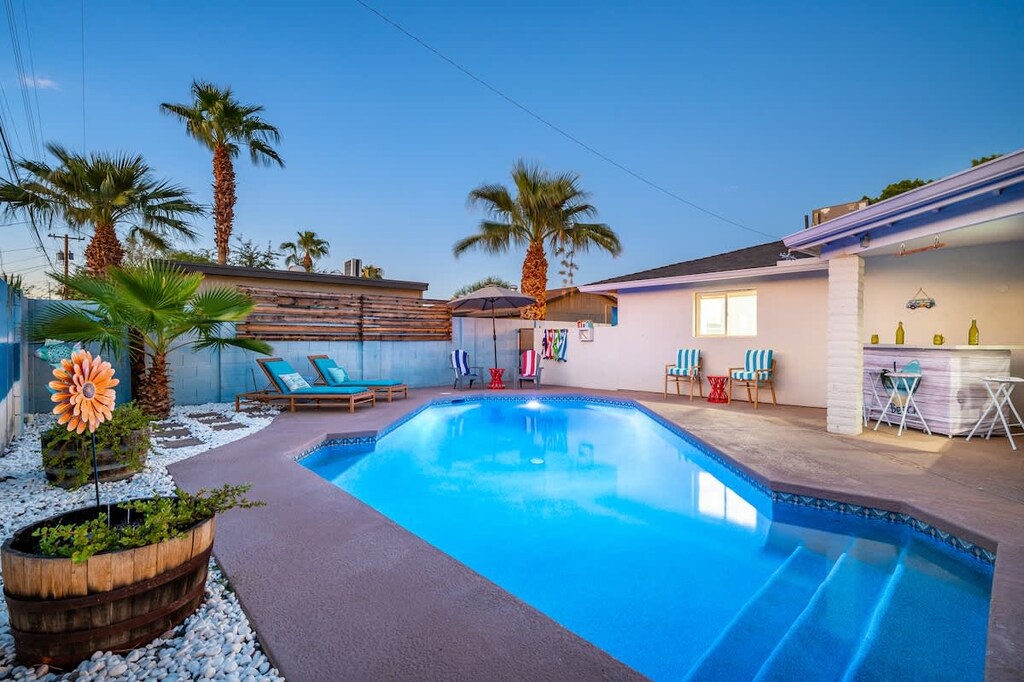Private backyard with a pool, outdoor seating, fire pit, sun loungers, bar area, mini golf, covered patio, outdoor dining area, grill, and corn hole.