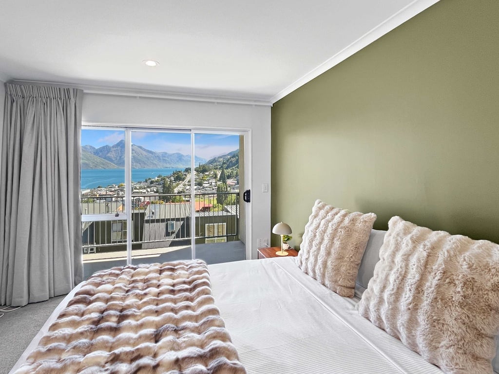 Spacious bedroom opening to balcony and lake views
