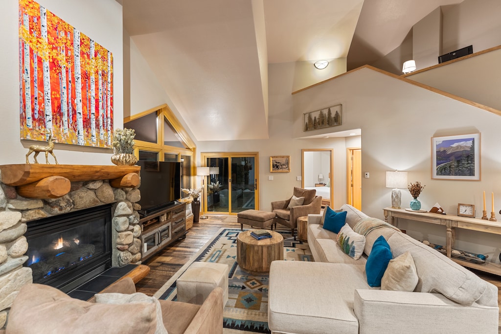 Cozy up by your crackling stone fireplace in this spacious living room, where plush seating and mountain views create the perfect retreat.