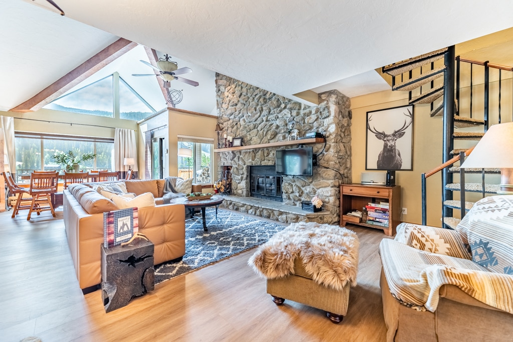 Cozy up by the stone fireplace in this inviting living space with soaring ceilings and mountain views.
