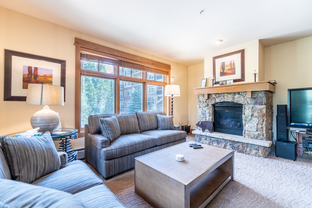 Unwind in your cozy living space with plush seating, warm fireplace, and large windows framing peaceful views—perfect for relaxing after mountain adventures.