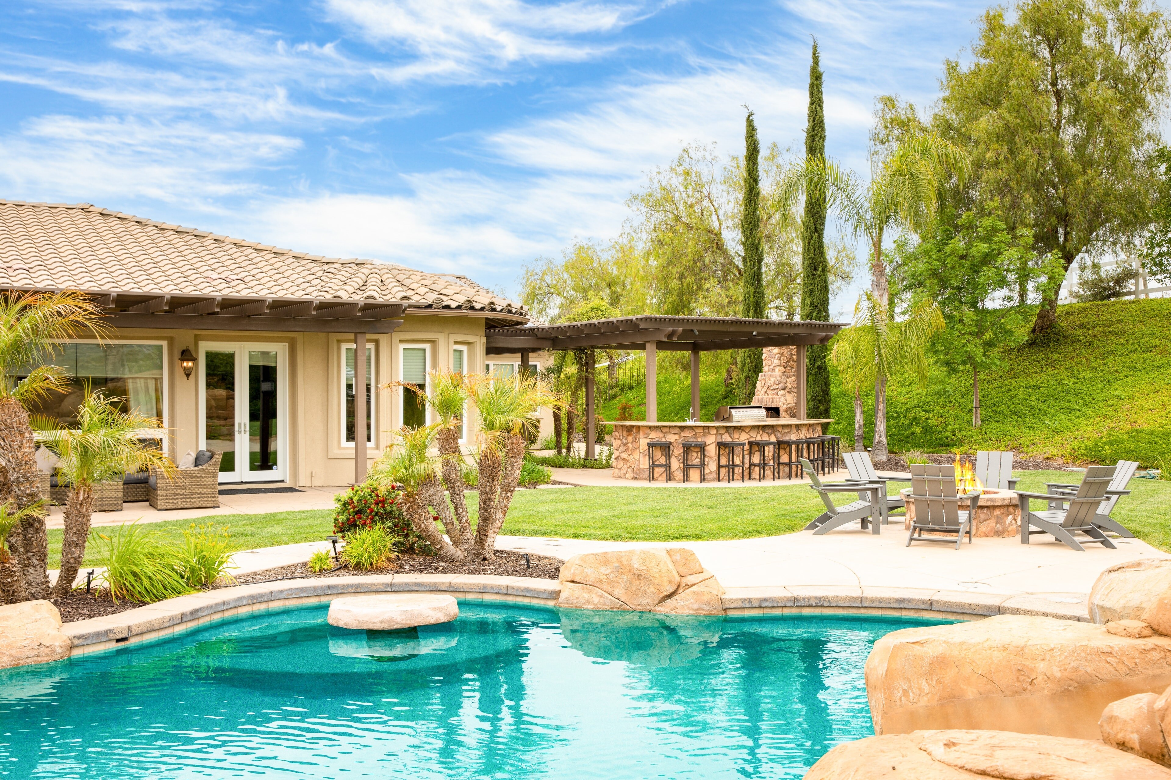 The private entertainer's backyard features a pool, hot tub, and plenty of lounge spaces to enjoy the outdoors.