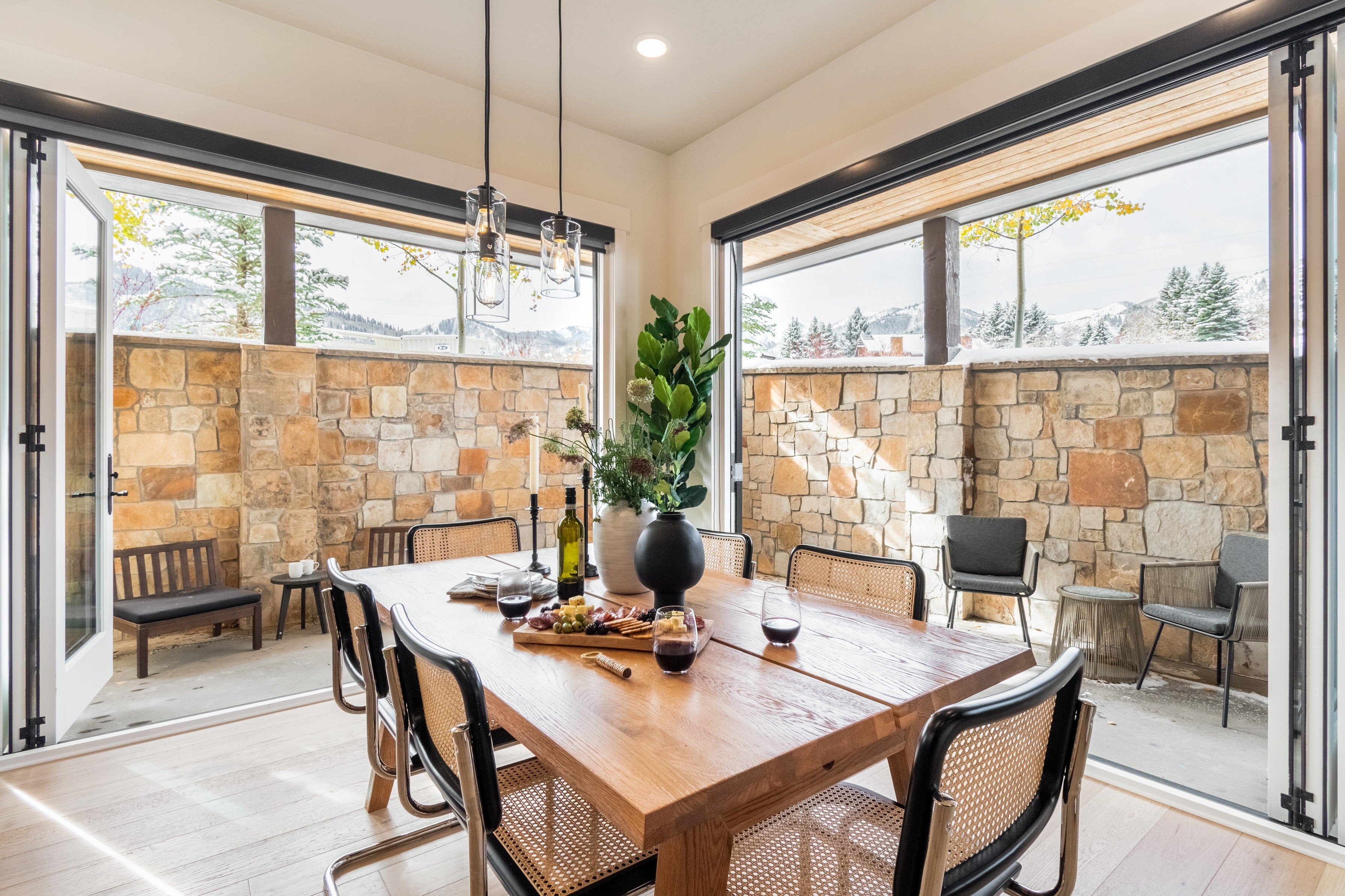 Dining table is surrounded by large doors leading to the patio.