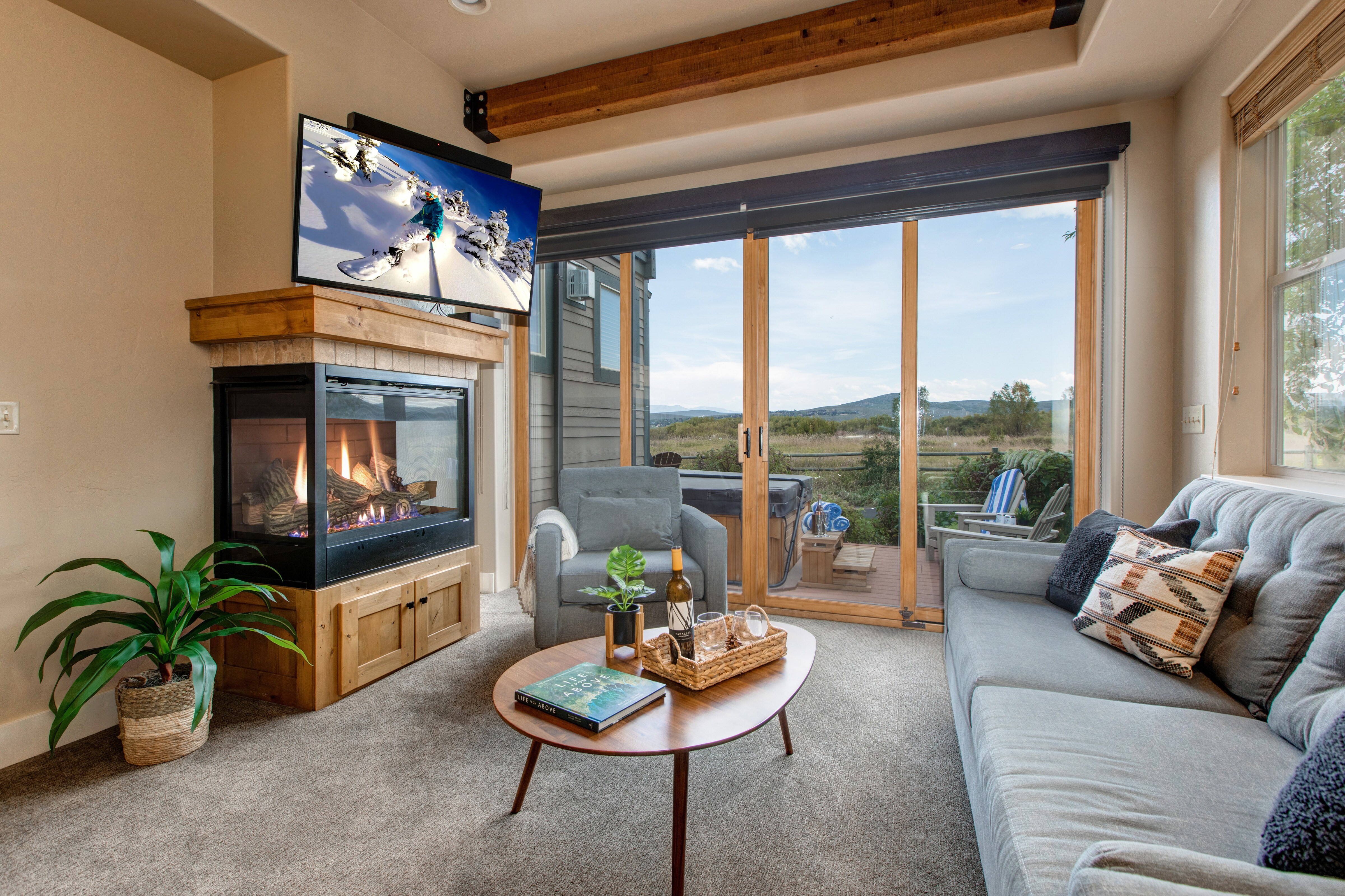 Living Room with plush couch, armchair, gas fireplace, 50" TV, and private hot tub patio access
