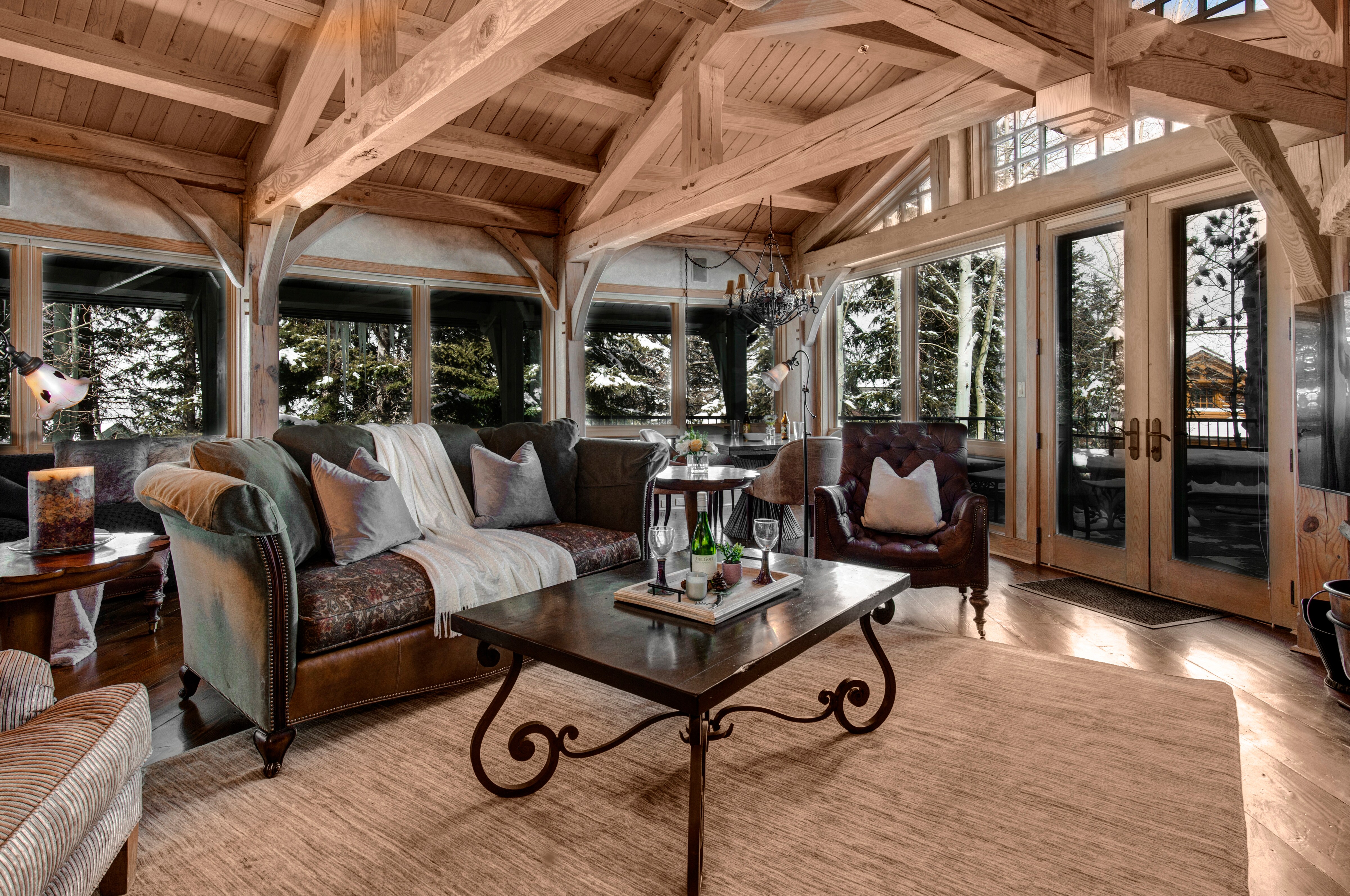 Main Level Living Room encased in natural light, with plush furniture, private deck access, gas-assist fireplace, 65" Samsung smart tv, marble game table, and stunning ski resort views