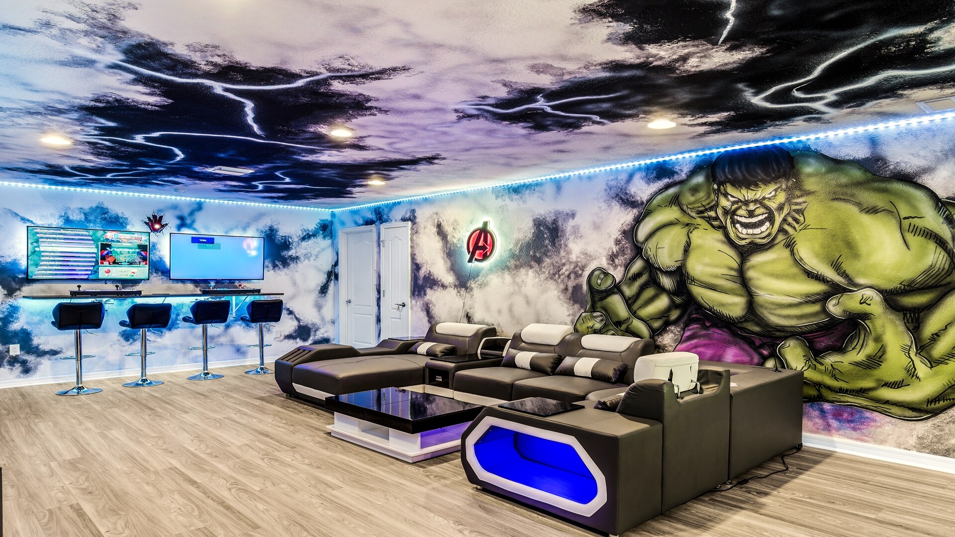 Marvel themed loft room with 3 large screen TVs and a bar seating area.