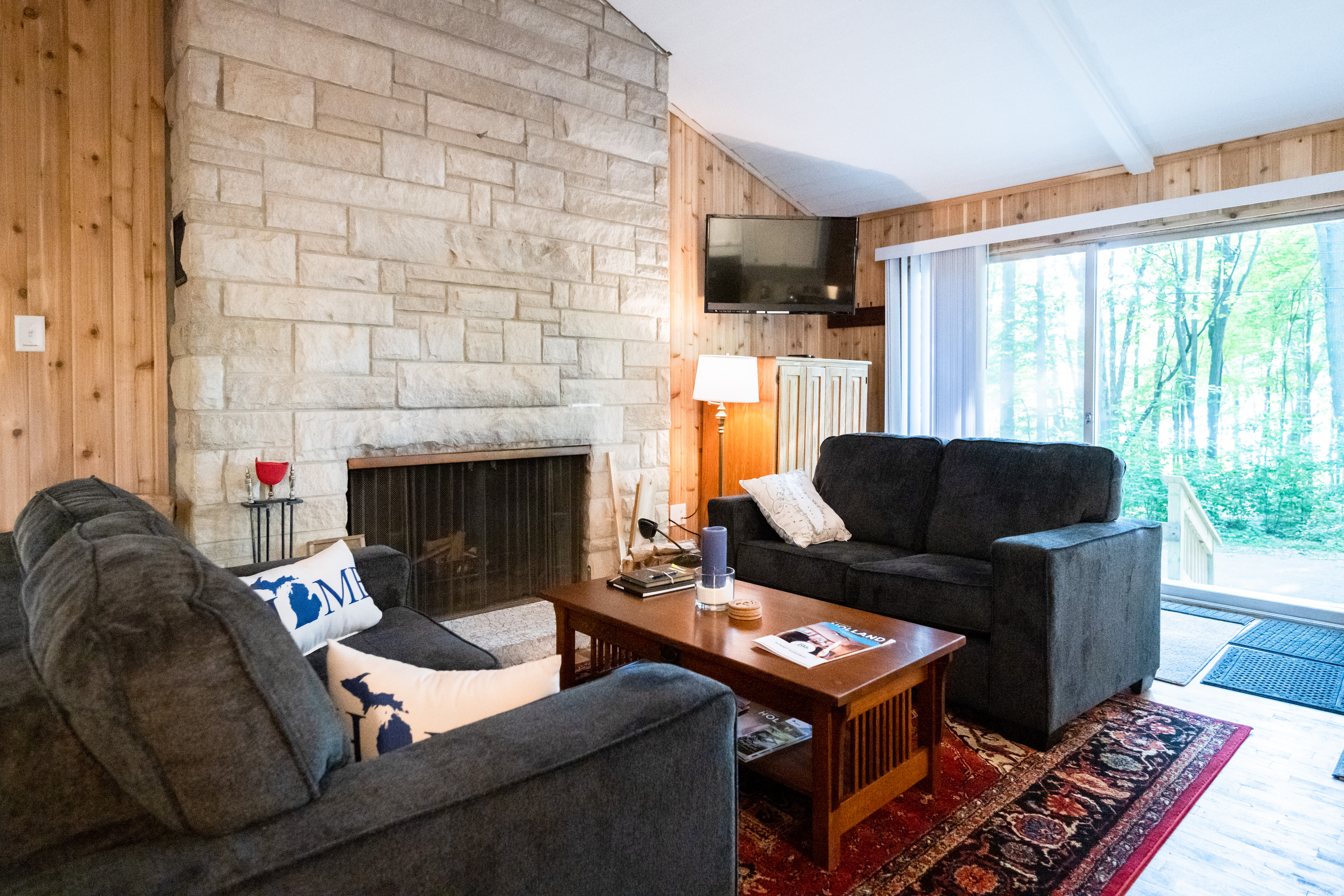 Open living room features stone wall, flat screen tv and double loveseats.